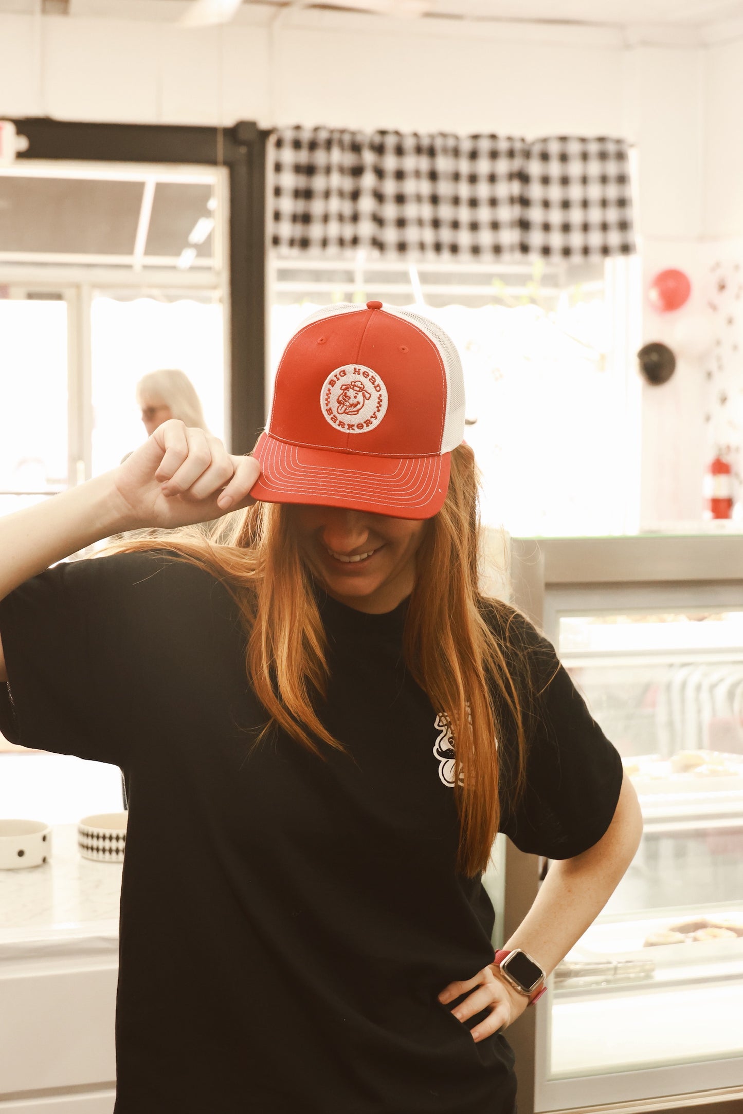 Person wearing a red cap with a logo in a casual setting