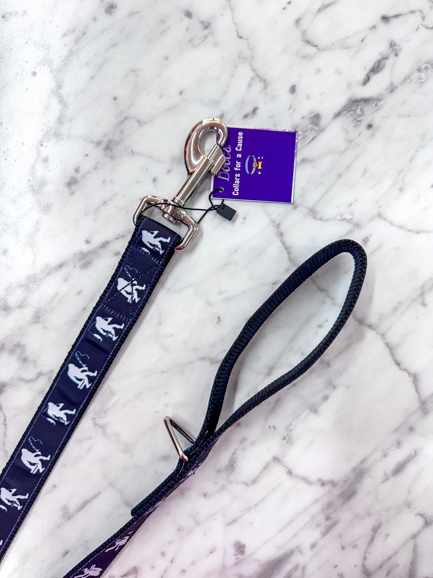 Navy blue dog leash with white illustrations on a marble surface