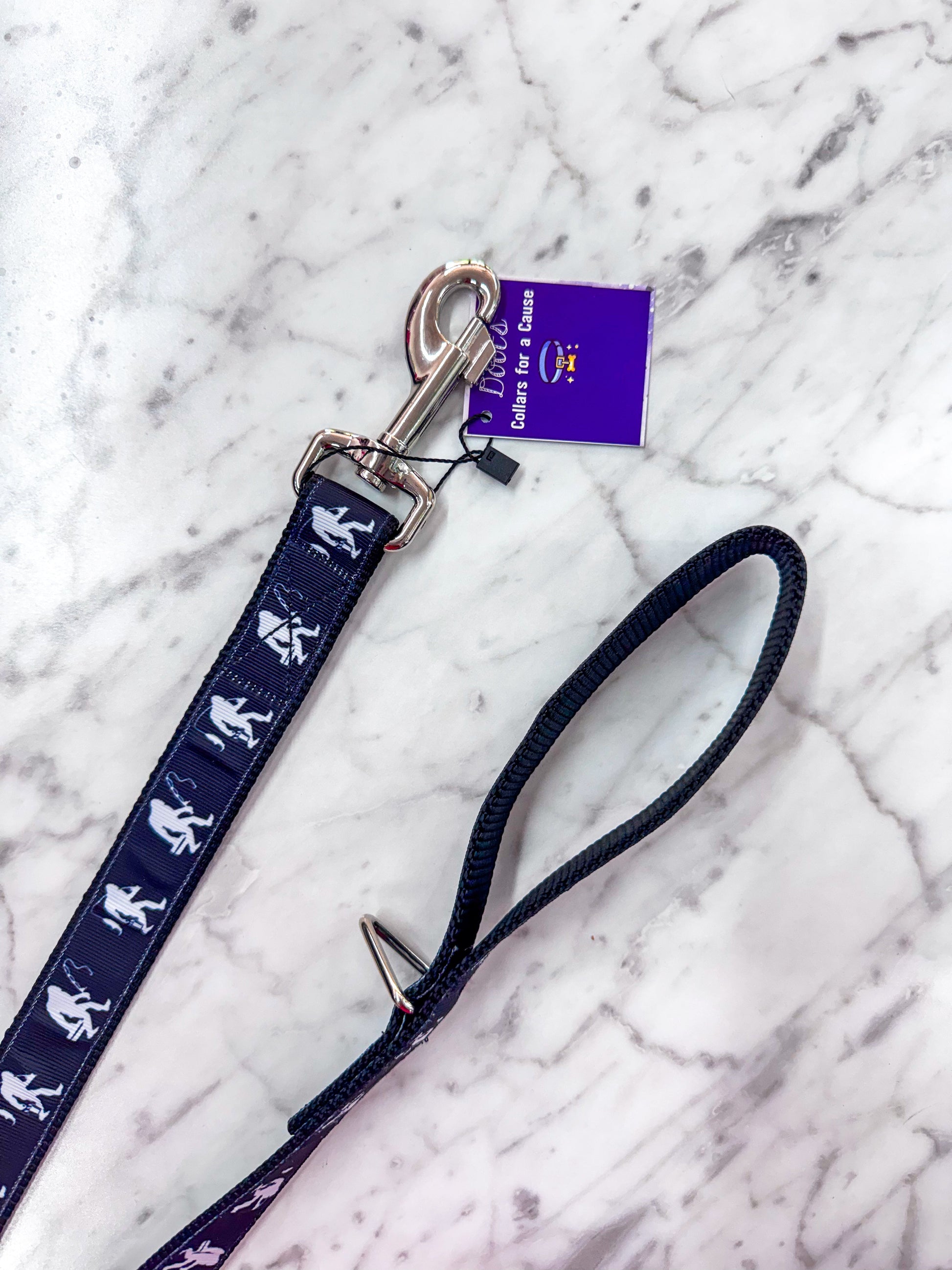 Navy blue dog leash with white illustrations on a marble surface