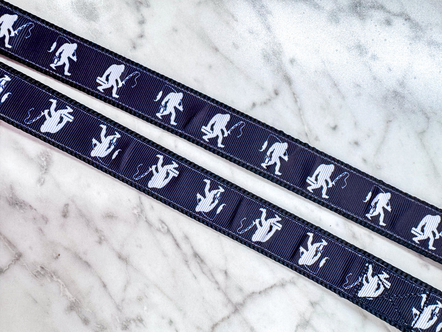 Navy blue ribbon with white silhouette patterns of a person sitting on a log on a marble surface