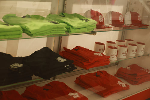 Display of green, red, and black merchandise including shirts, hats, and cups.