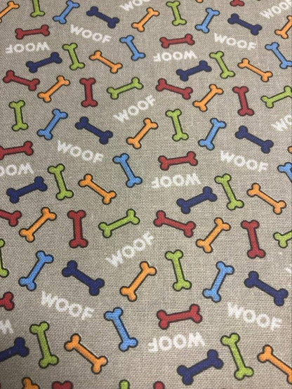 Pattern of colorful dog bones and 'WOOF' text on a beige background